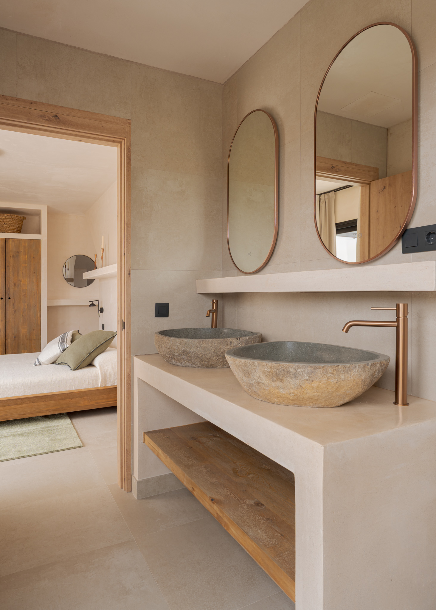 Ensuite bathroom with double stone basin vanity, oval mirrors and copper fixtures